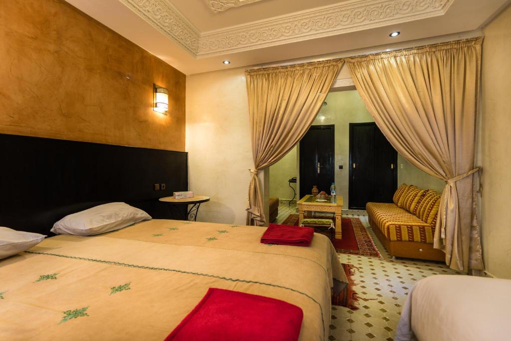 une chambre d'hôtel avec deux lits et un canapé dans l'établissement Riad Omar, à Marrakech