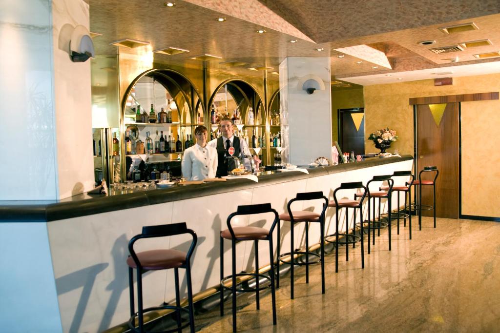 un bar avec une rangée de tabourets dans un restaurant dans l'établissement Hotel Diplomat Palace, à Rimini