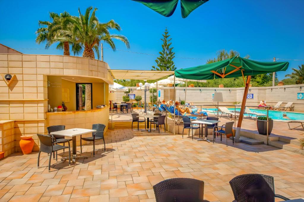 un patio avec tables et chaises à côté d'une piscine dans l'établissement Hotiday Cefalù Mazzaforno, à Cefalù