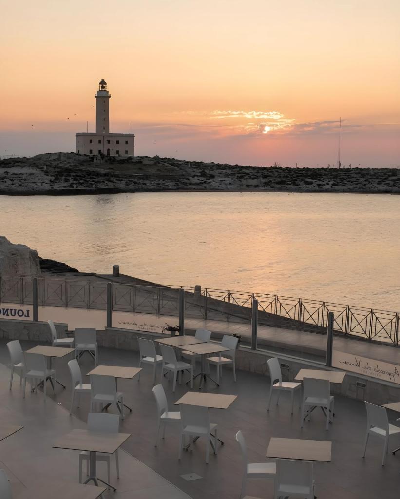 un groupe de tables et de chaises devant un phare dans l'établissement HOTIDAY Vieste Lungomare, à Vieste