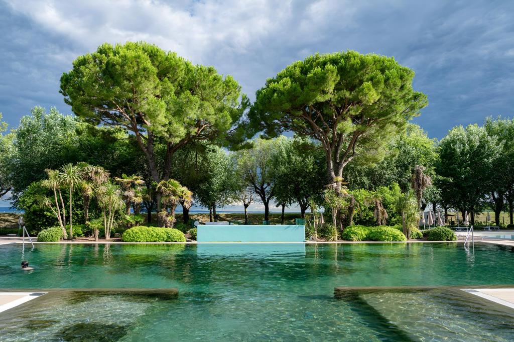 un bassin d'eau avec des arbres en arrière-plan dans l'établissement HOTIDAY Room Collection - Grado, à Grado
