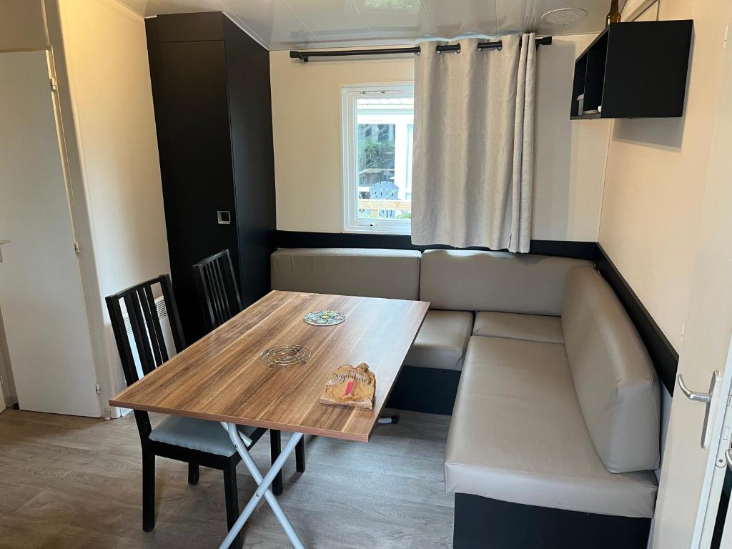 une salle à manger avec une table et un canapé dans l'établissement Charmant Mobil home 6 places, à Carnac
