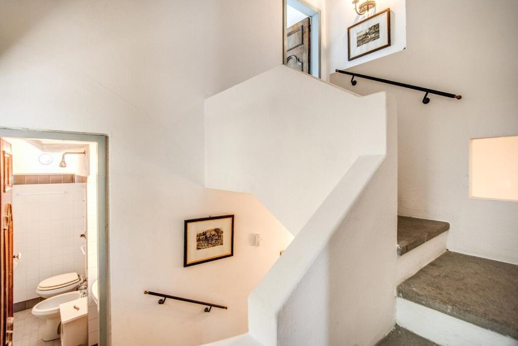 La salle de bains blanche est pourvue d'un escalier et de toilettes. dans l'établissement Villa Monticello, private pool and timeless beauty, à Massa Lubrense