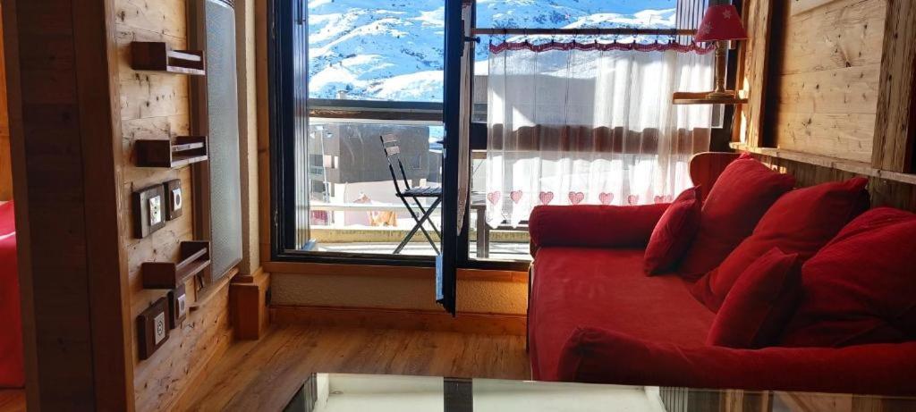 - un salon avec un canapé rouge et une grande fenêtre dans l'établissement Mountain dream family, aux Menuires