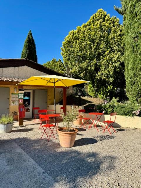 un patio avec une table, des chaises et un parasol dans l'établissement CAMPING GINASSERVIS Mobile-home Flores, à Ginasservis