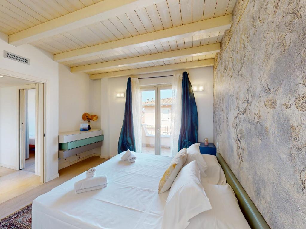 - une chambre avec un grand lit blanc et des rideaux bleus dans l'établissement Villa Dolcevita by Bookinggardalake, à Manerba del Garda
