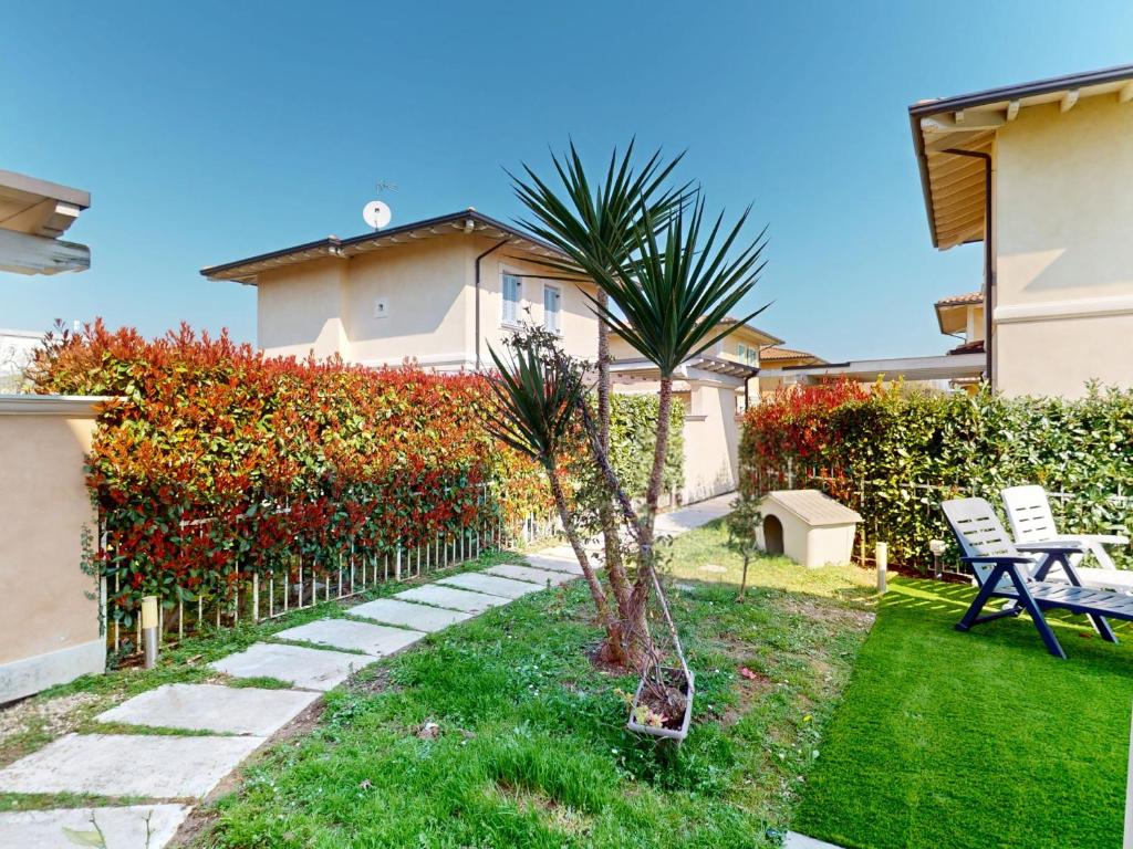 un jardin avec un palmier et une balançoire dans l'établissement Villa Dolcevita by Bookinggardalake, à Manerba del Garda