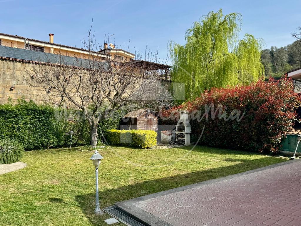 un jardin avec un arbre et un train en arrière-plan dans l'établissement Villa Viviana con Piscina "UnaNotteaCasaMia", à Sacrofano