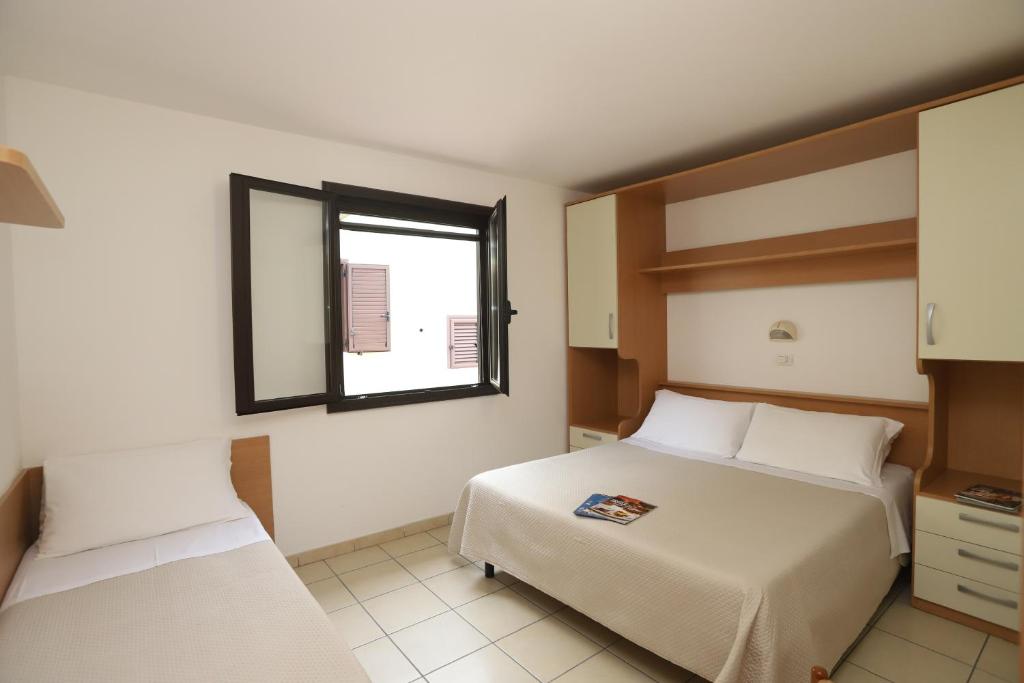 une chambre avec deux lits et une fenêtre dans l'établissement Residence Club Solemare, à Vieste