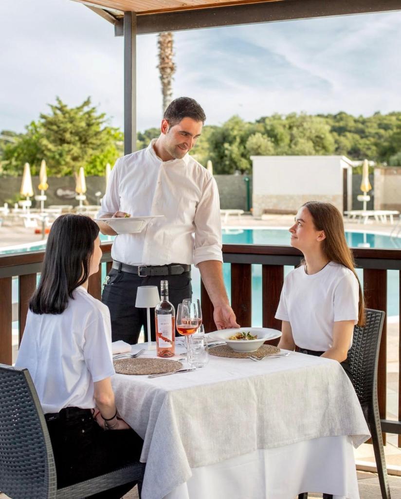 un homme tenant une assiette de nourriture à une table dans l'établissement Residence Club Solemare, à Vieste 83 autres photos