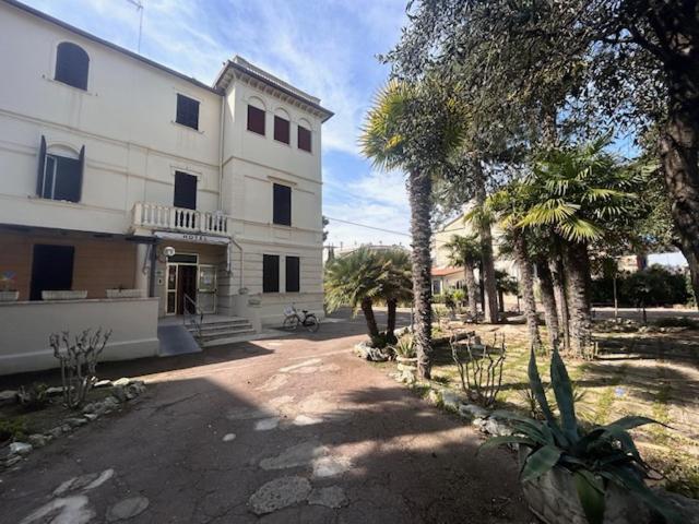 un grand bâtiment blanc avec des palmiers devant dans l'établissement Hotel VILLA PINA, à Senigallia