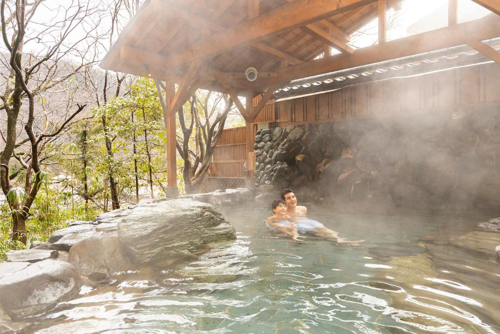 2 personnes se baignant dans une source chaude à dans l'établissement Ooedo Onsen Monogatari Premium Yamanaka Grand Hotel, à Kaga