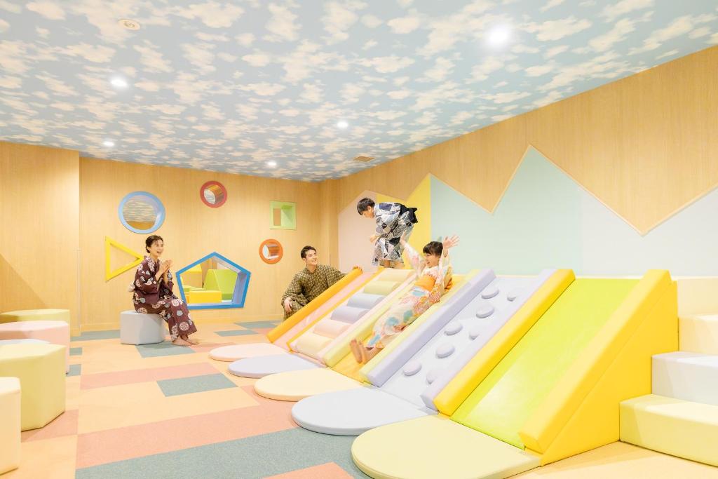 une pièce avec des enfants jouant sur un toboggan dans l'établissement Ooedo Onsen Monogatari Premium Yamanaka Grand Hotel, à Kaga