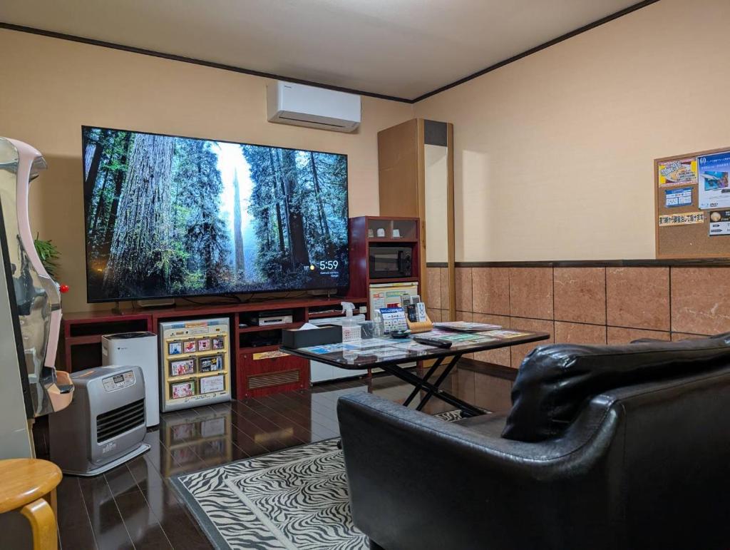 un salon avec une grande télévision à écran plat dans l'établissement ホテル ツインビー, à Yabase