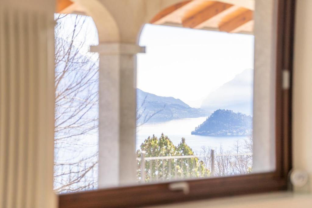 un miroir reflétant une fenêtre avec vue sur le lac dans l'établissement Villa Lumbini, à Plesio