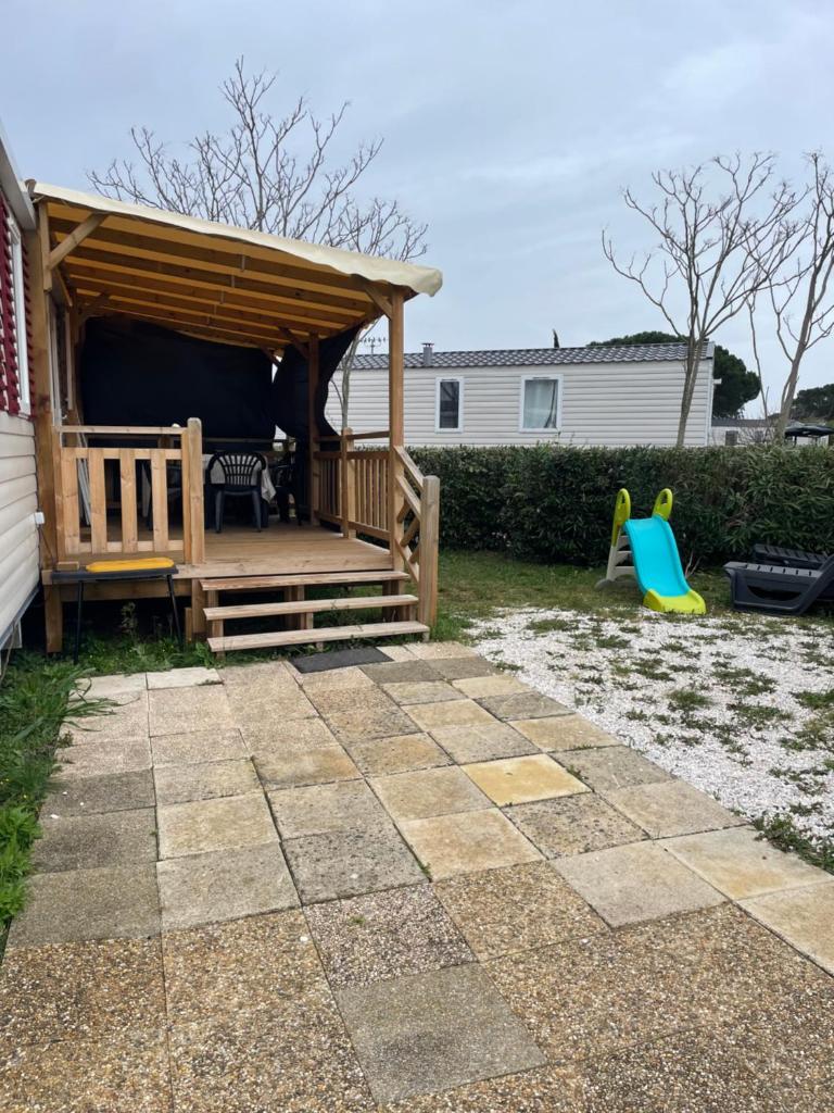 une cour avec un kiosque en bois et une aire de jeux dans l'établissement Mobil home 6-8pers - Le lac des rêves, à Lattes