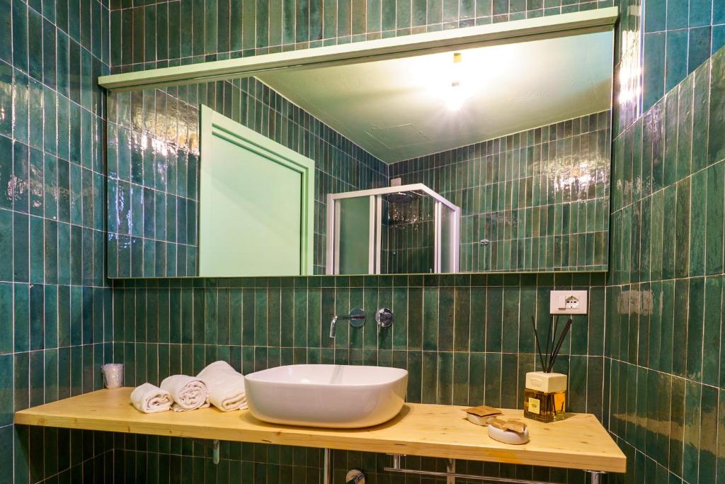 une salle de bain carrelée verte avec un lavabo et un miroir dans l'établissement CSA Hotel Beach & Park, à Marina di Bibbona