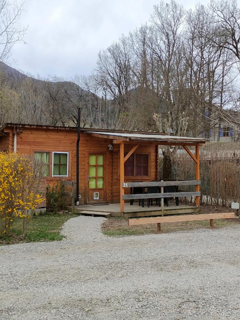 une cabane en rondins avec une véranda et une clôture dans l'établissement Camping du Moulin de Thoard, à Thoard