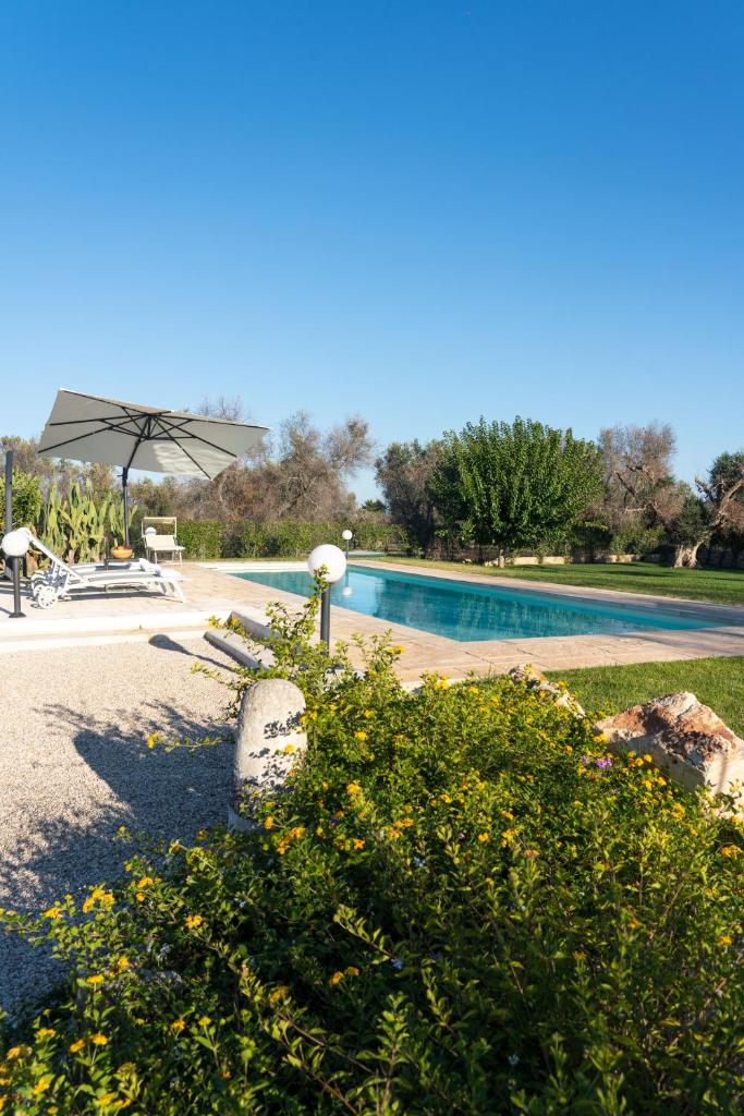 - une piscine avec une table et un parasol dans l'établissement Villa L'Ulivo by Bianco Puglia Vacanze, à San Vito dei Normanni