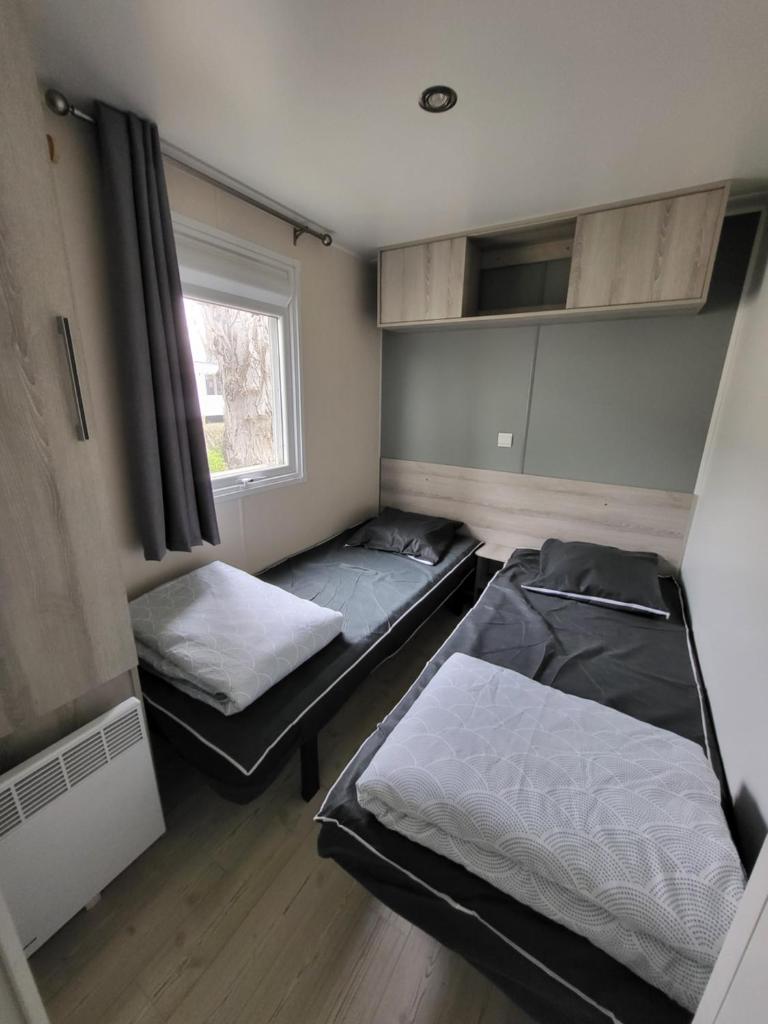 deux lits dans une chambre avec une fenêtre dans l'établissement Te Mahana La Carabasse, à Vias