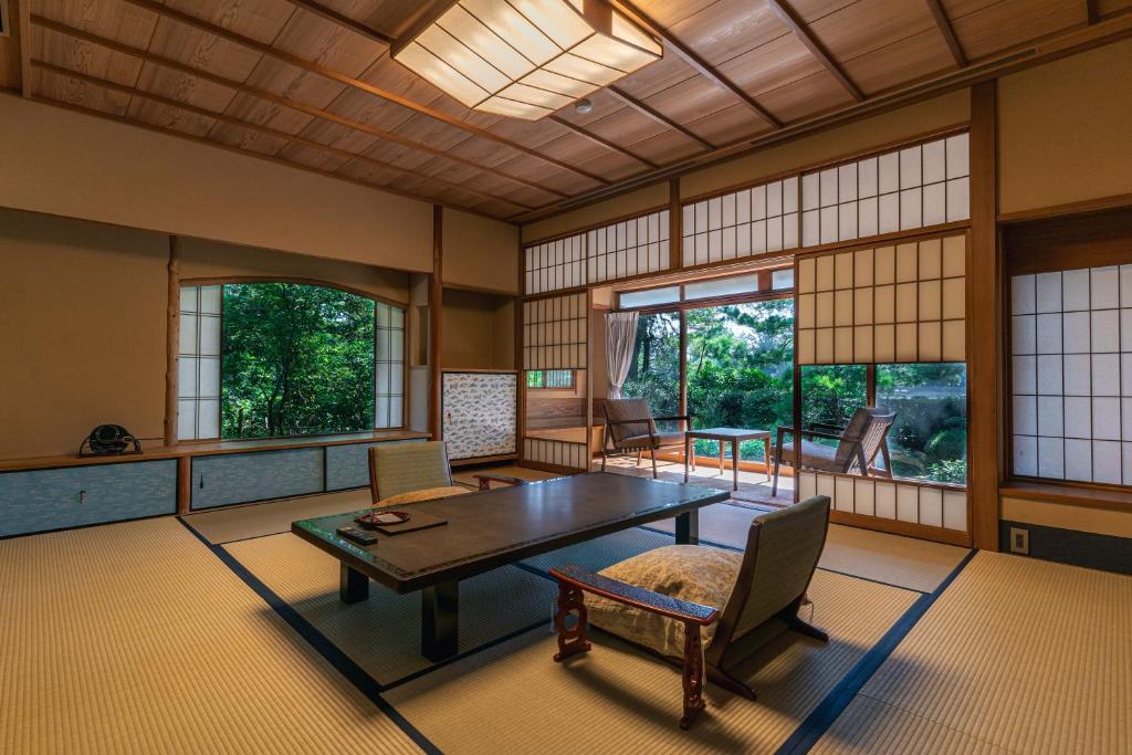 une pièce avec une table, des chaises et des fenêtres dans l'établissement Monjusou Shourotei, à Miyazu