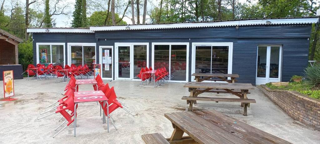 un groupe de tables de pique-nique et de bancs devant un bâtiment dans l'établissement Les mobil homes d’oliver rob, à Saint-Chéron