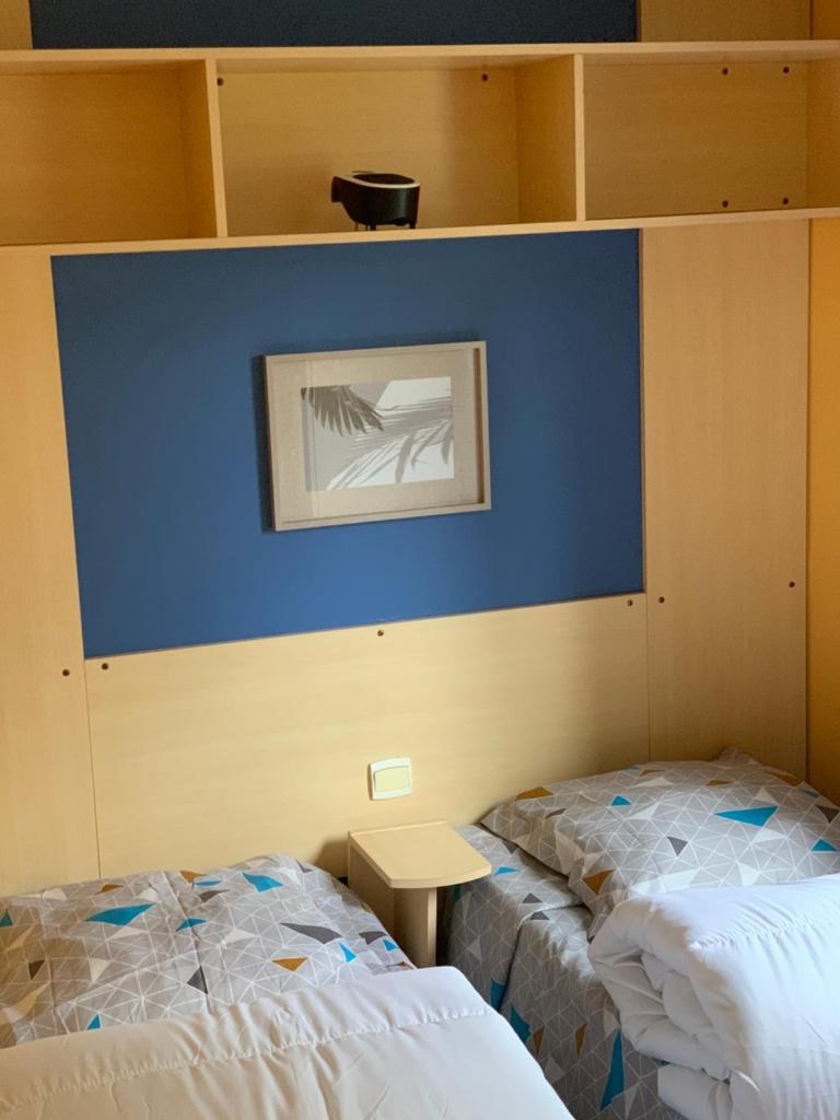 - 2 lits dans une chambre avec un mur bleu dans l'établissement Les mobil homes d’oliver rob, à Saint-Chéron