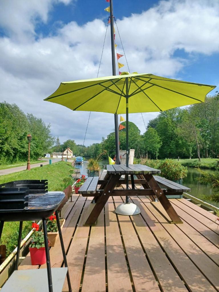 - une table de pique-nique avec un parasol jaune sur un quai dans l'établissement Sur la Somme à bord de la péniche Arche de Noé, à Pont-Rémy