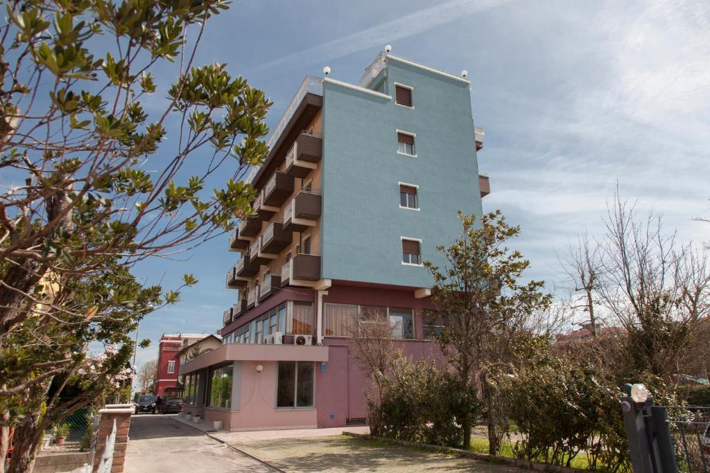 un bâtiment rose et bleu dans une rue dans l'établissement Hotel Concorde, à Bellaria-Igea Marina