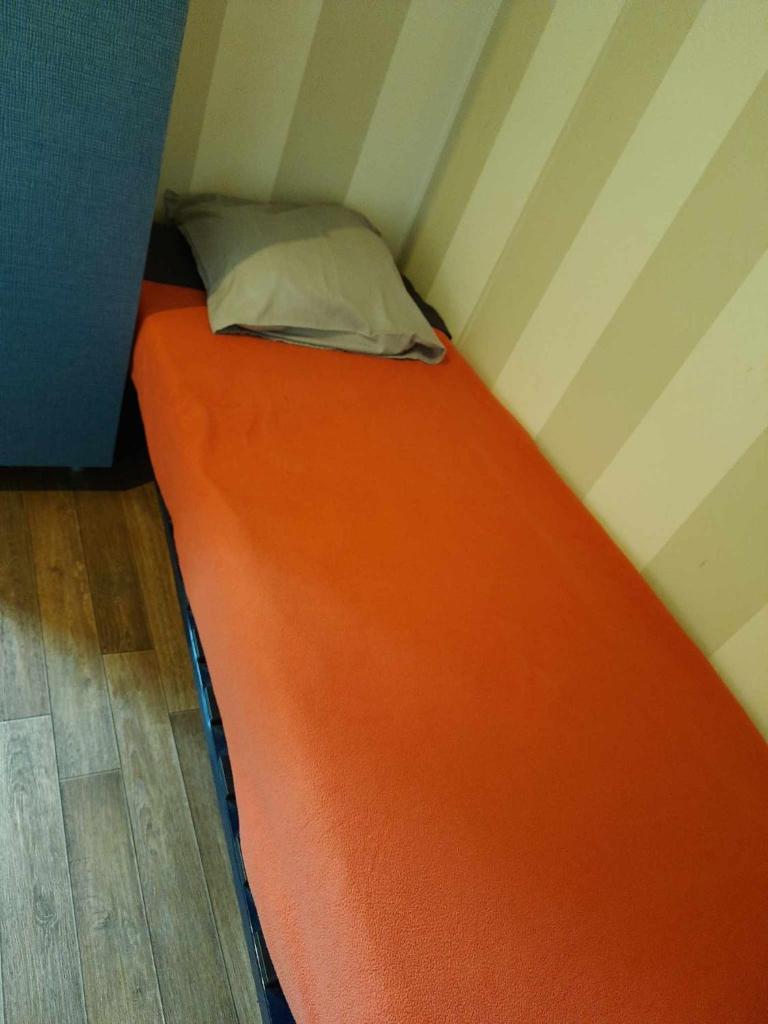 Ce lit se trouve dans une petite chambre dotée d'un matelas orange. dans l'établissement Mobil home - N025, à Boofzheim