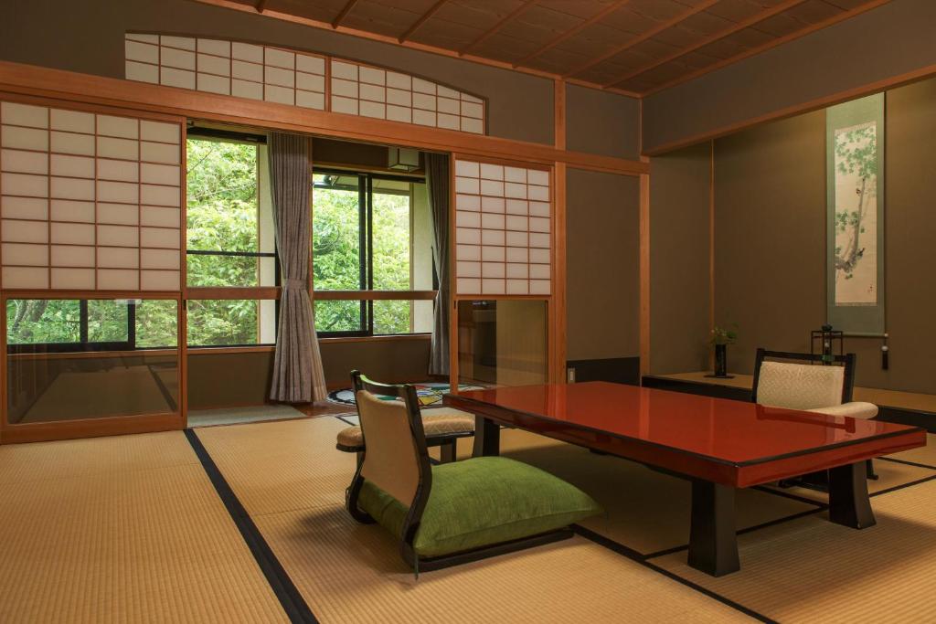 un salon avec une table, des chaises et des fenêtres dans l'établissement Kocho, à Kaga