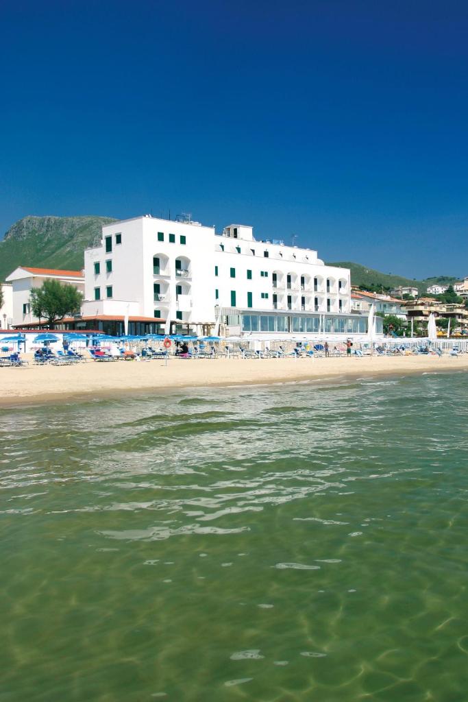 une plage avec un grand bâtiment blanc et l'eau dans l'établissement Hotel Amyclae, à Sperlonga