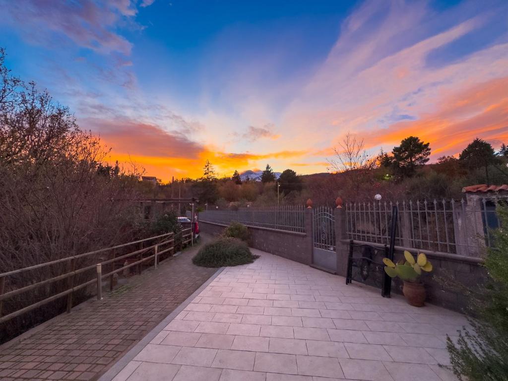 un coucher de soleil sur une clôture et un sentier dans l'établissement Villa del Gelso - Chalet nel Parco dell'Etna, à Mascali