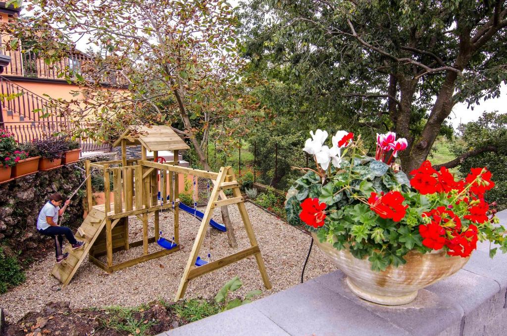 un vase avec des fleurs rouges à côté d'une balançoire dans l'établissement Villa del Gelso - Chalet nel Parco dell'Etna, à Mascali