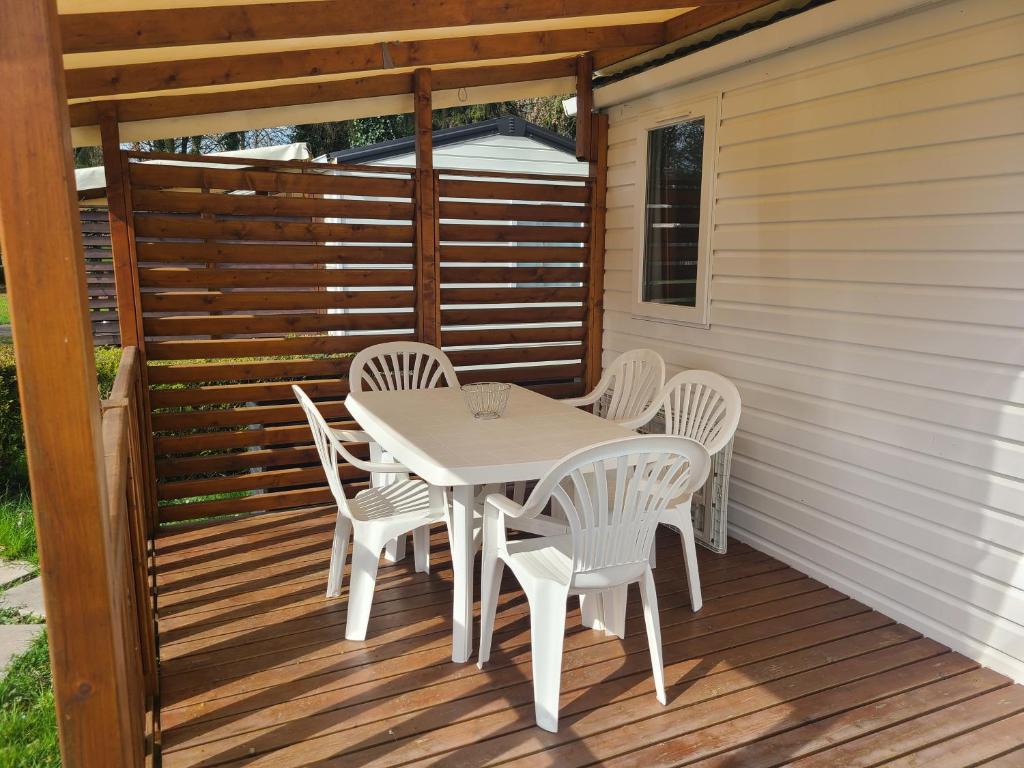 une table et des chaises blanches sur une terrasse en bois dans l'établissement chez audrey C21, à Boofzheim