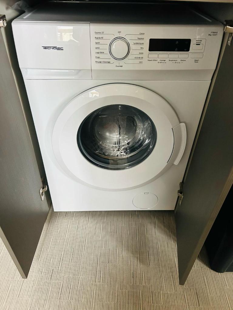 - un lave-linge avec une porte ouverte dans une pièce dans l'établissement Mobilhome la Carabasse 40m2 6-8 personnes, à Vias