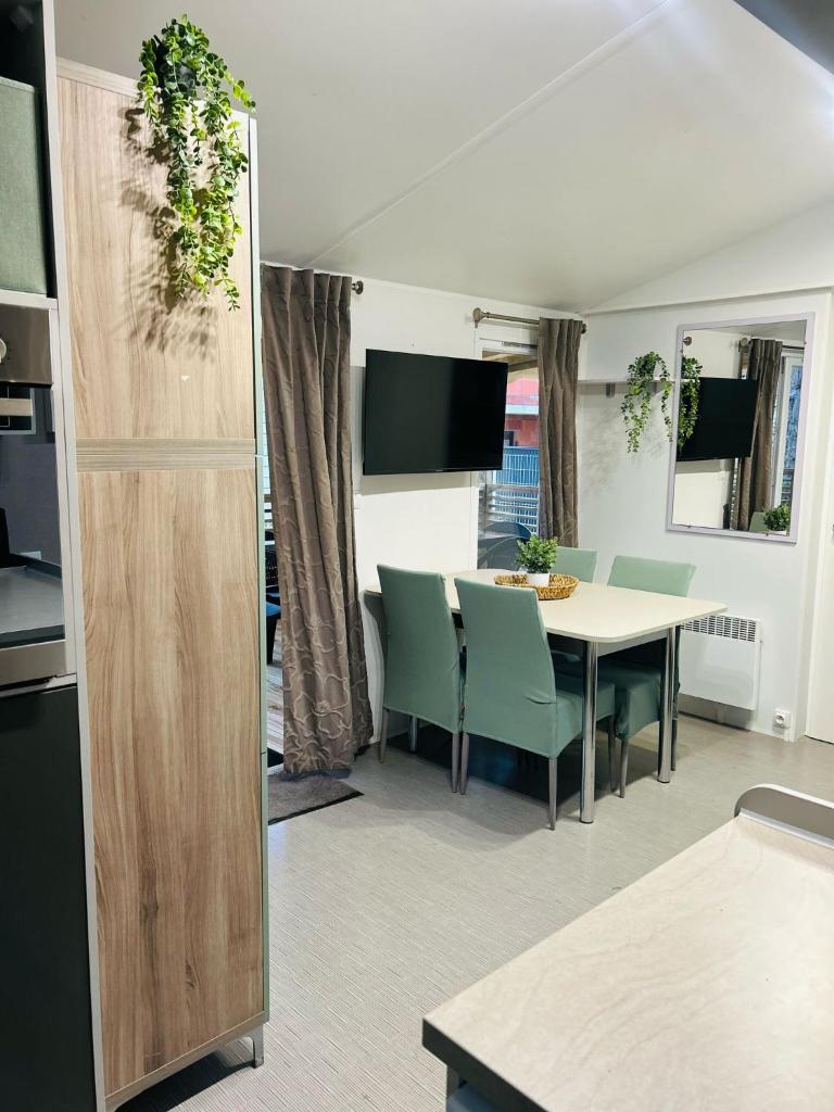 une cuisine et une salle à manger avec une table et des chaises dans l'établissement Mobilhome la Carabasse 40m2 6-8 personnes, à Vias