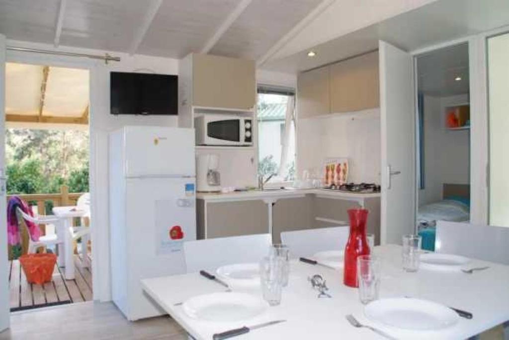 - une cuisine avec deux tables blanches et un réfrigérateur blanc dans l'établissement Camping 3 étoiles - Parc aquatique - eecehf, à Fréjus