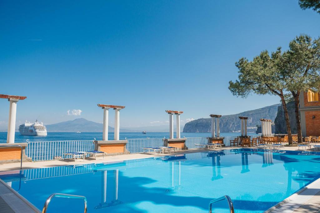une piscine avec un bateau de croisière dans l'eau dans l'établissement Grand Hotel Europa Palace Sorrento, à Sorrente