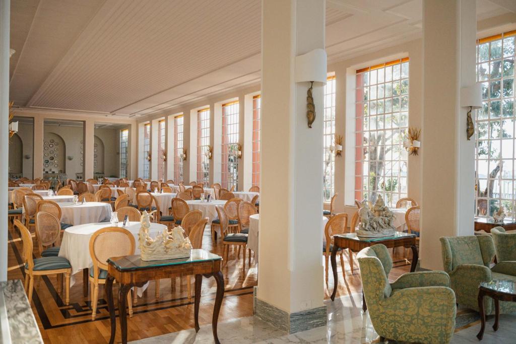 une salle à manger avec tables, chaises et fenêtres dans l'établissement Grand Hotel Europa Palace Sorrento, à Sorrente
