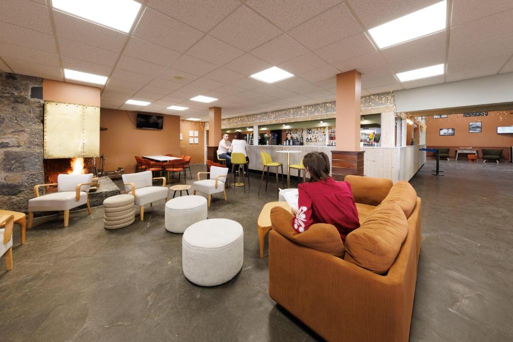 une femme assise sur un canapé dans une salle d'attente dans l'établissement Belambra Clubs Superbesse - Le Chambourguet, à Super-Besse 25 autres photos