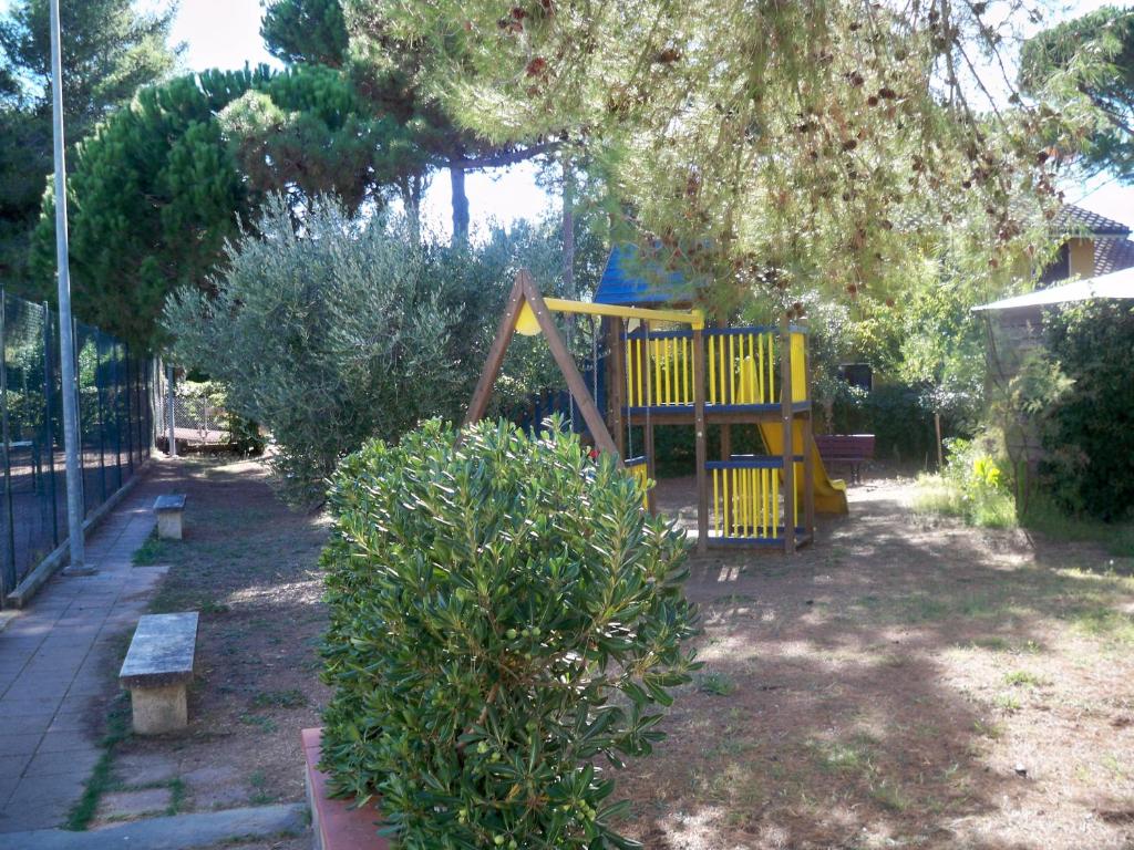 une aire de jeux dans une cour avec un arbre dans l'établissement Residence Airone, à Orbetello