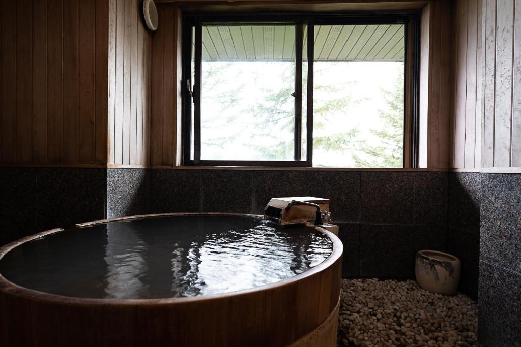 une baignoire dans une pièce avec une fenêtre dans l'établissement Hotel Kanronomori, à Niseko