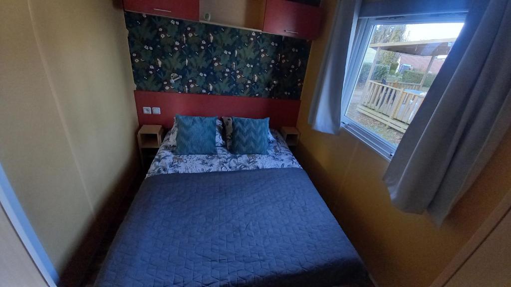 un petit lit dans une chambre avec une fenêtre dans l'établissement location mobil-home le parc des roches, à Saint-Chéron