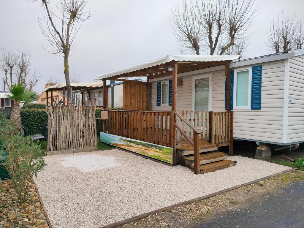 une petite maison avec un porche et une clôture dans l'établissement Mobil-home Les Locs Danous, à Valras-Plage