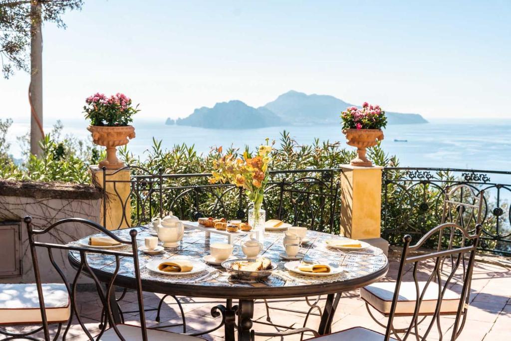 une table avec des assiettes de nourriture sur un balcon dans l'établissement Villa Murat Historic Residence with Heated Pool and Còncierge by Feeling Italy, à Massa Lubrense