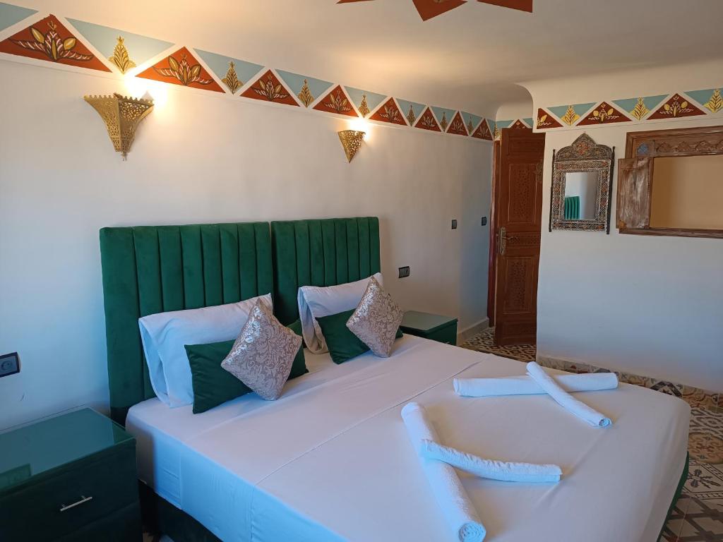- une chambre avec un grand lit blanc et une tête de lit verte dans l'établissement Riad Amira Fes, à Fès
