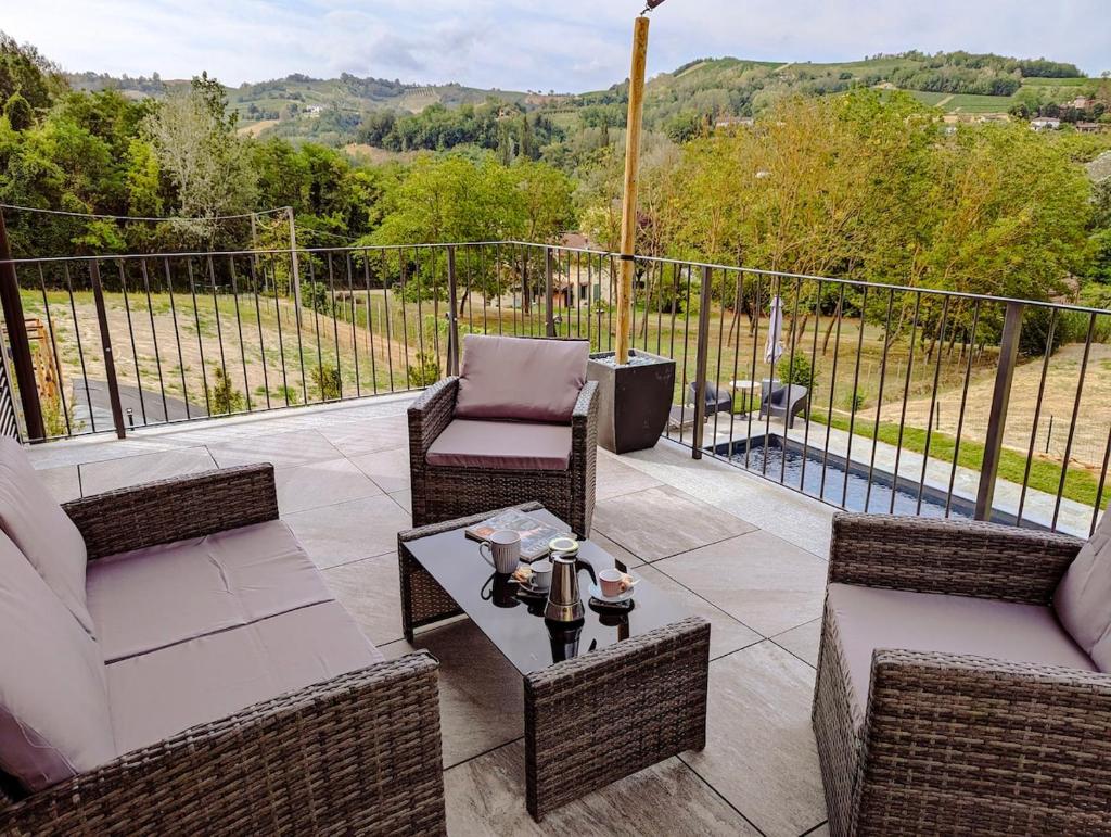 une terrasse avec des chaises en osier, une table et une piscine dans l'établissement Villa Grassi with private pool Nizza Monferrato, à Calamandrana