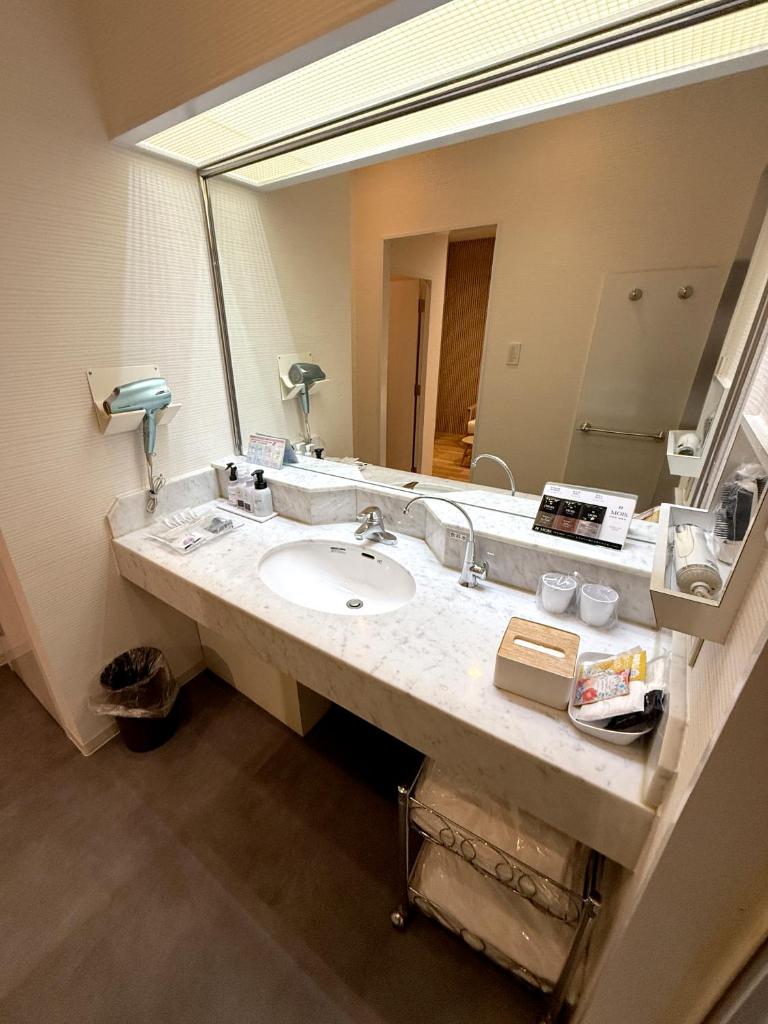 une salle de bain avec un lavabo et un grand miroir dans l'établissement Hotel Hyper (Adult Only), à Osaka