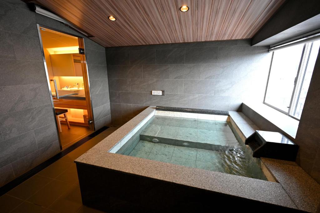une grande baignoire dans une pièce avec une fenêtre dans l'établissement Matsubaya Ryokan, à Kyoto